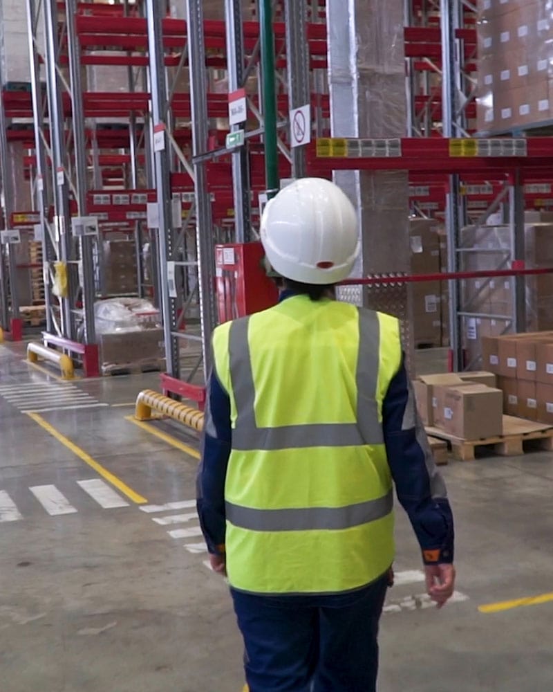 woman in high-vis jacket walking through isles of cargo Import From India